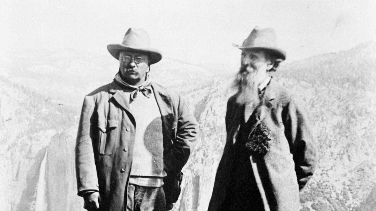Theodore Roosevelt and John Muir stand together in front of Yosemite Falls