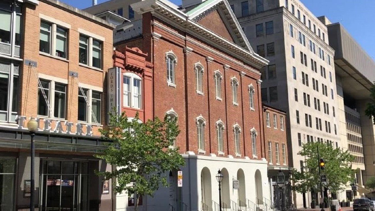 A brick building stands on a city street on a sunny day.