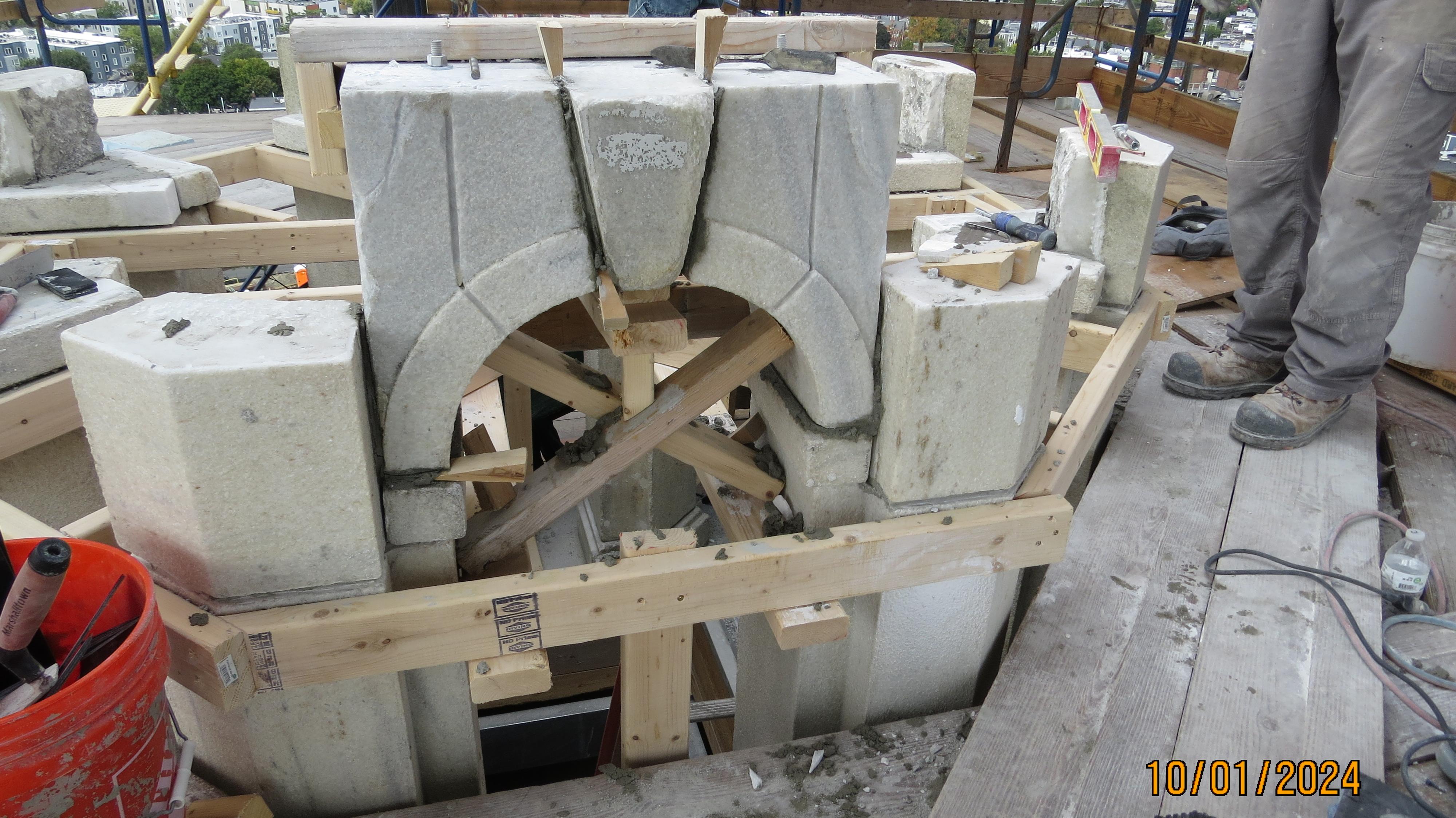 A granite arch for a window being put back together with wooden frame materials.