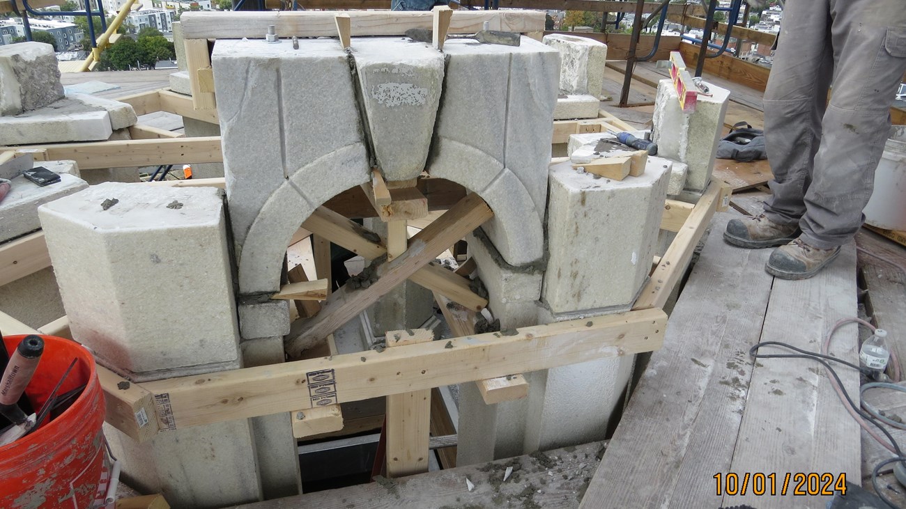 A granite arch for a window being put back together with wooden frame materials.