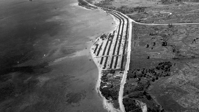 Ariel view of a village tucked between the ocean and a road