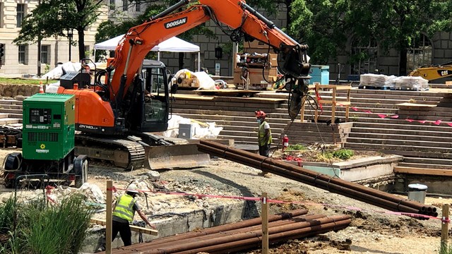 Pipes are offloaded by a crane in the dug-out area of the WWI Memorial