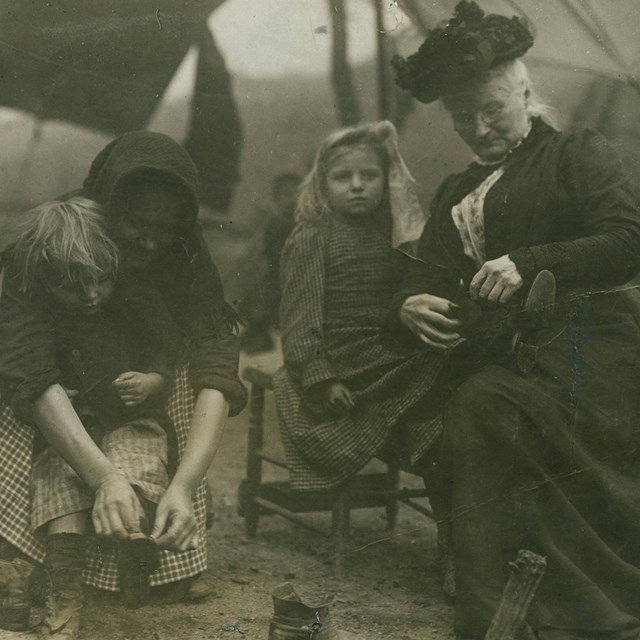 Women putting shoes on children