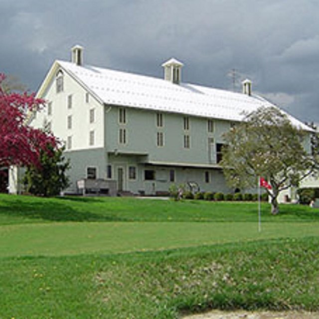 Photo of a white house in a green meadow. 