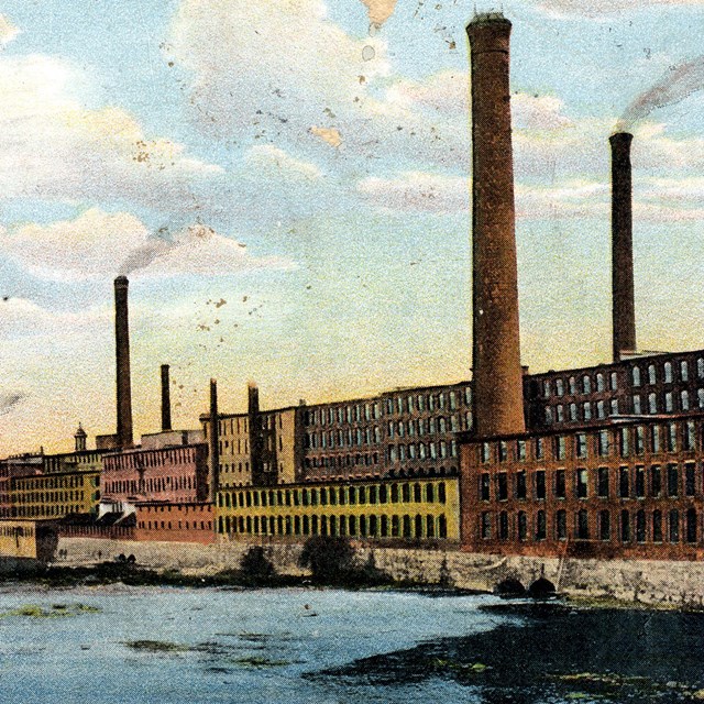 Postcard image of mill buildings along a river. 