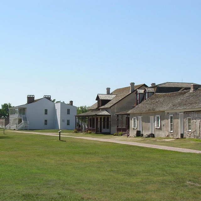 A grassy lawn leads to a group of historic buildings.