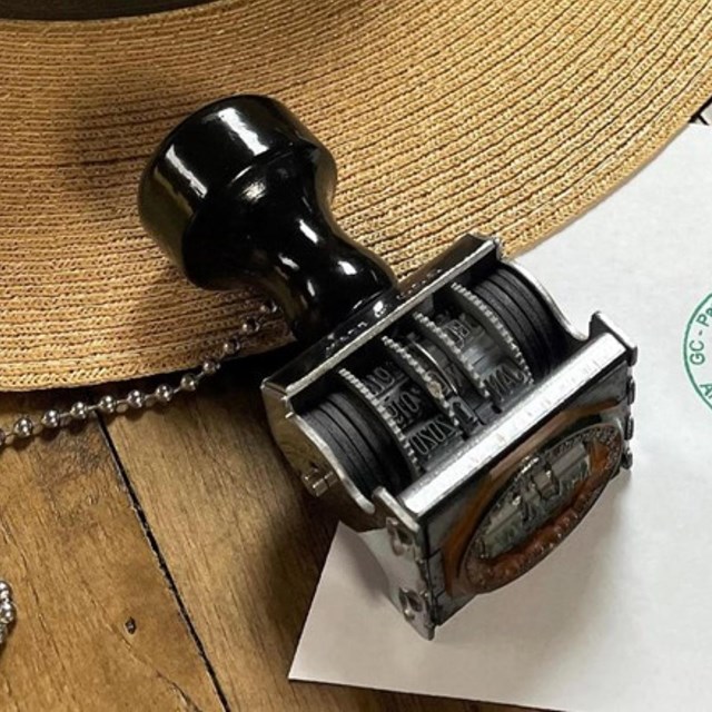 A ranger hat sits on a table next to a stamp and an ink pad.