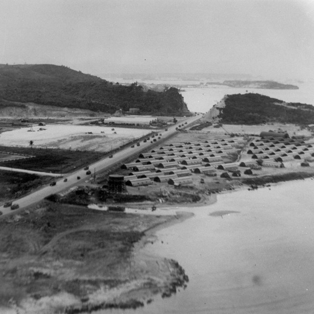 Military encampment with a highway running through it. The highway is full of military vehicles.