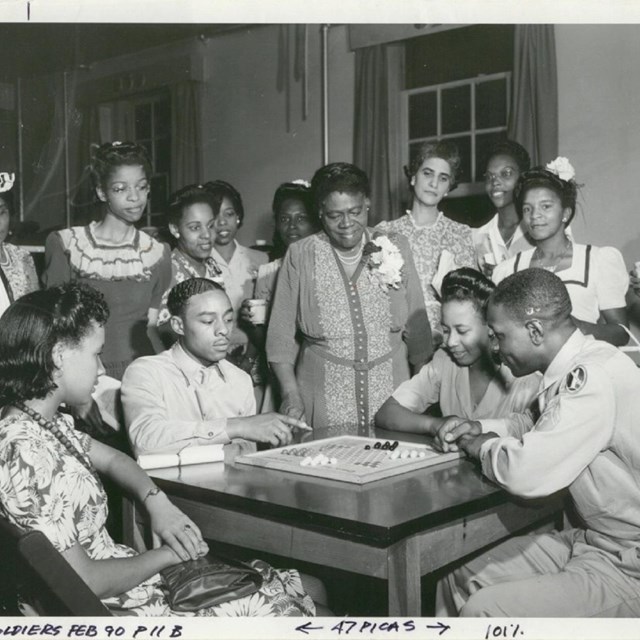 A group of African American people play or watch a board game