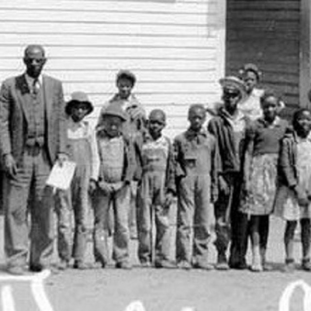 children in front of schoolhouse. 