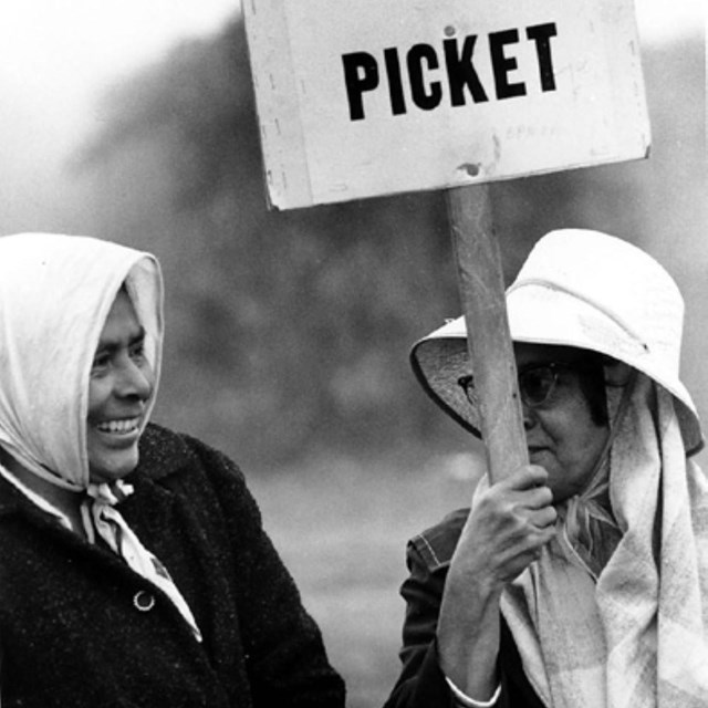 Two older women. One holds a labor protest sign.