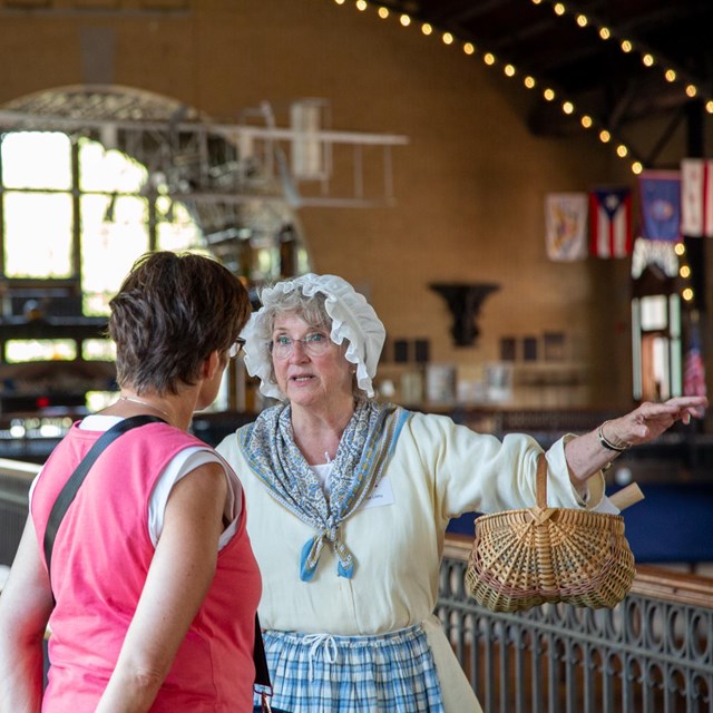 A woman in historical attire speaking to two others inside Dahlgren Hall