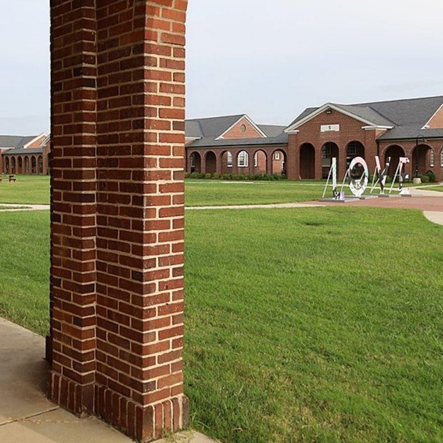 Brick building with arches with a grass-covered courtyard.