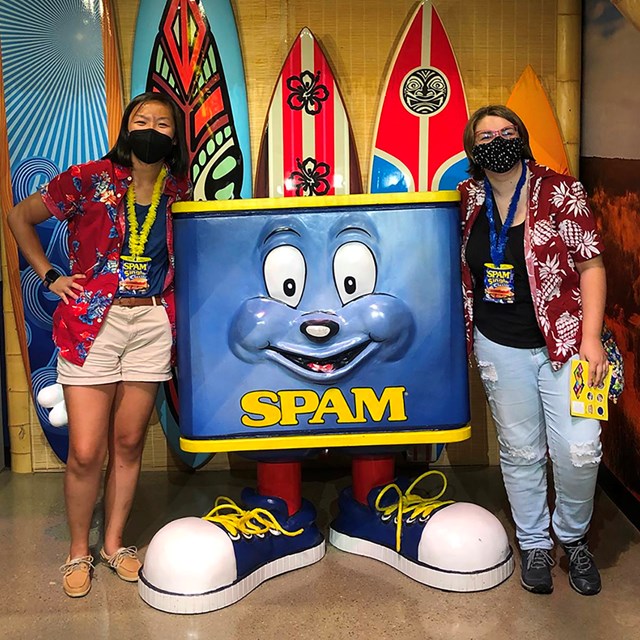 Two people pose with an anthropomorphic can of spam