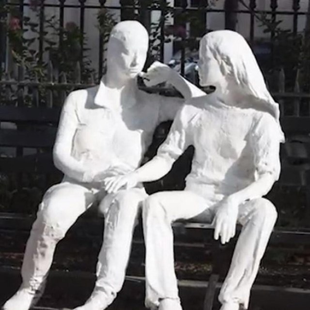 White plaster sculpture of two women sitting on a bench