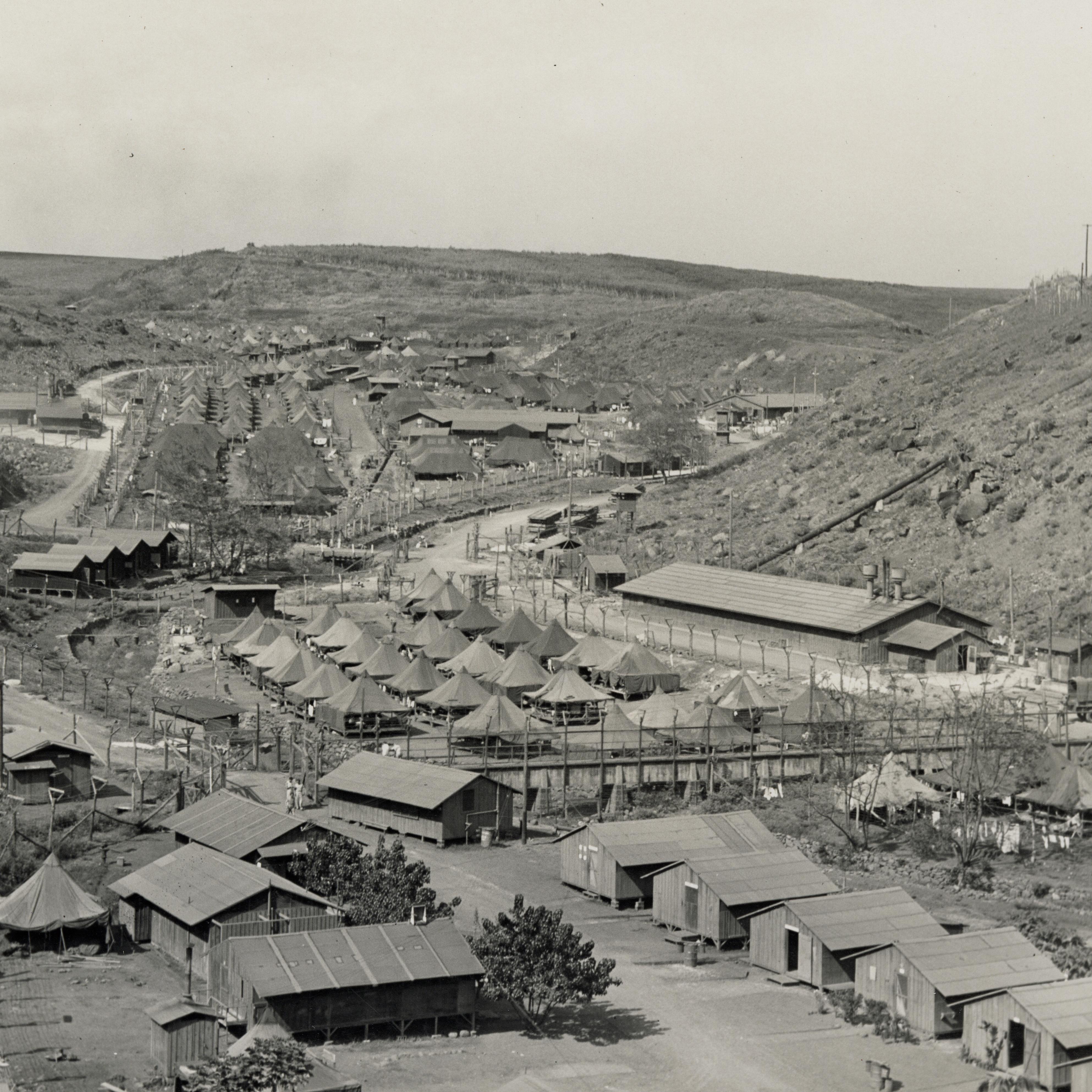 Small buildings and tents in the valley between large hills.