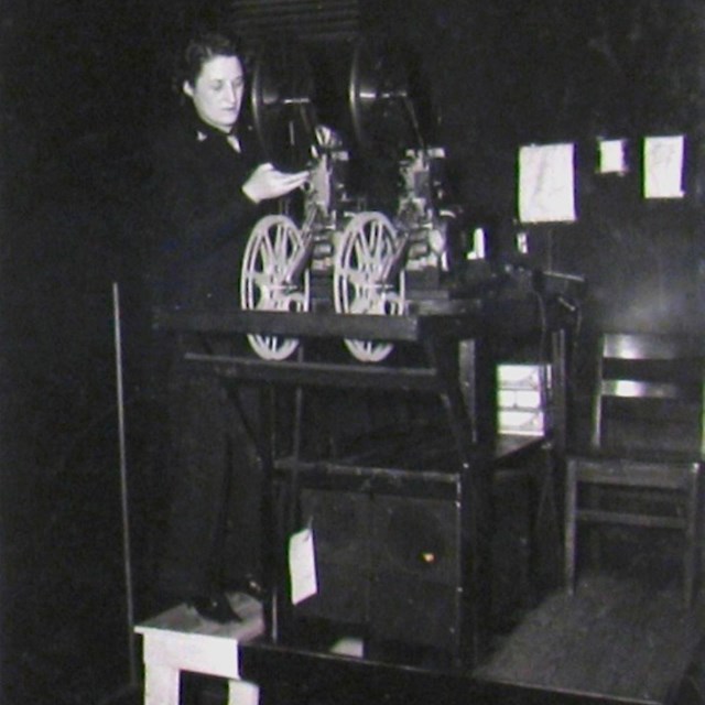 Black and white photo of a white woman working a projector