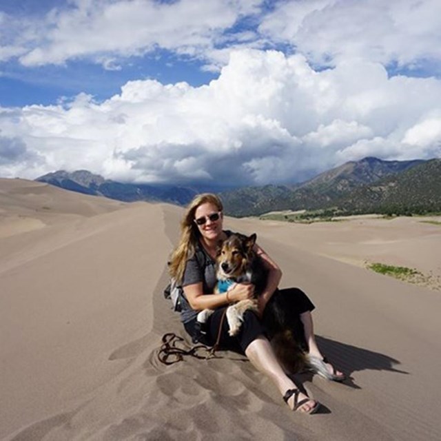 Susan sitting on a sand dune at Great Sand Dunes National Park. Photo courtesy Susan