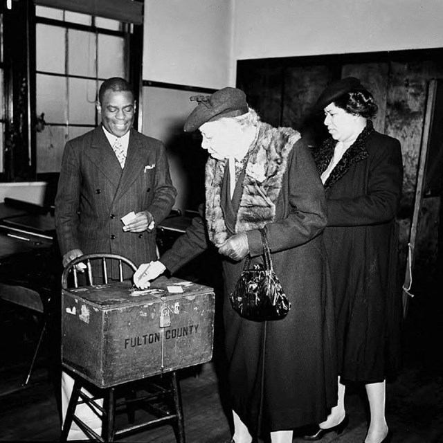 Black women putting ballots in a ballot box