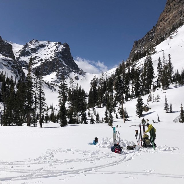 Skiers dig a snowpit with mountains in the background