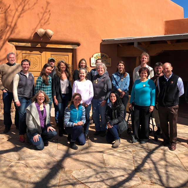 A group of people standing in front of a stucco building.