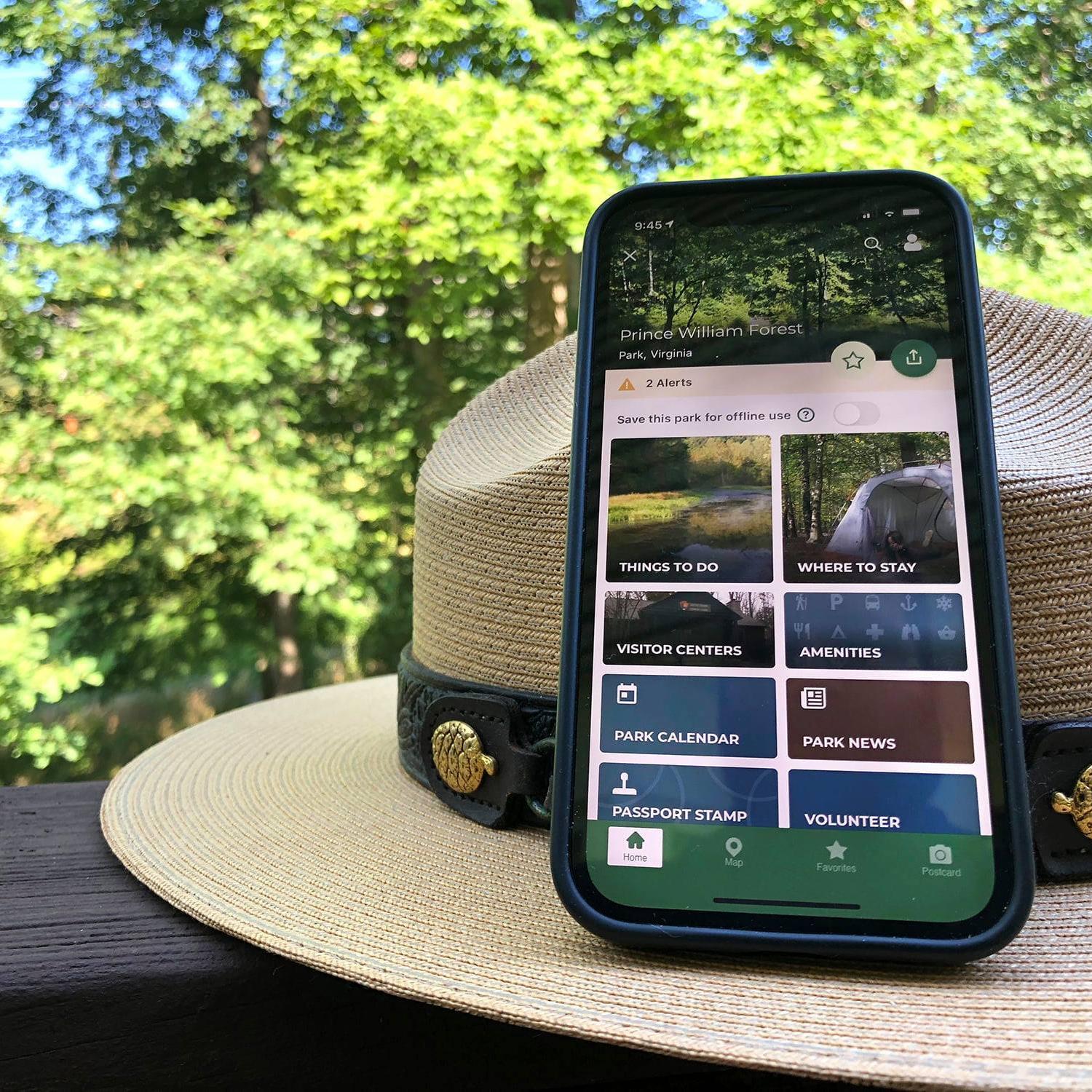 Smartphone displaying the NPS App while it sits on a ranger hat