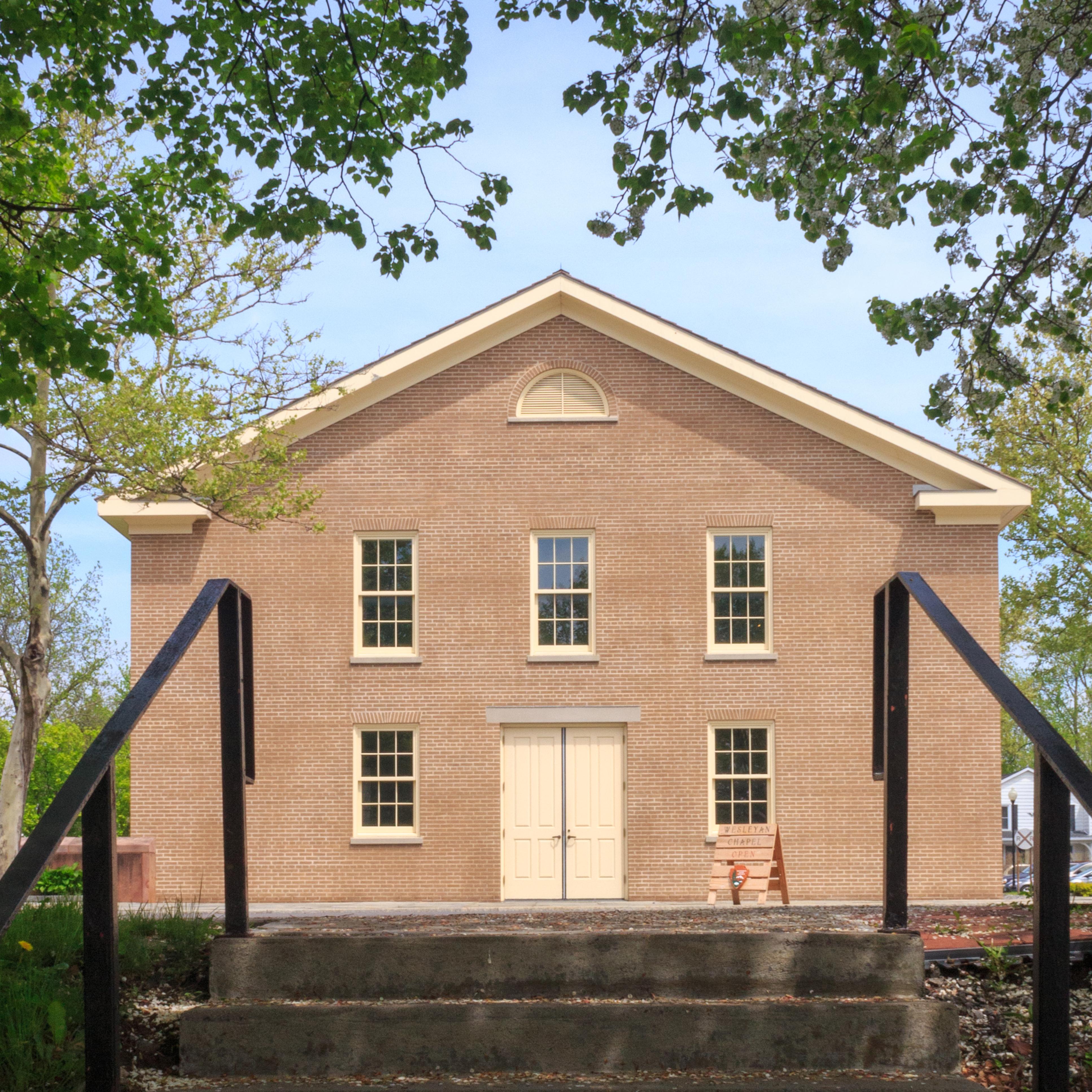 A square, two-story, red brick building with white-trimmed windows