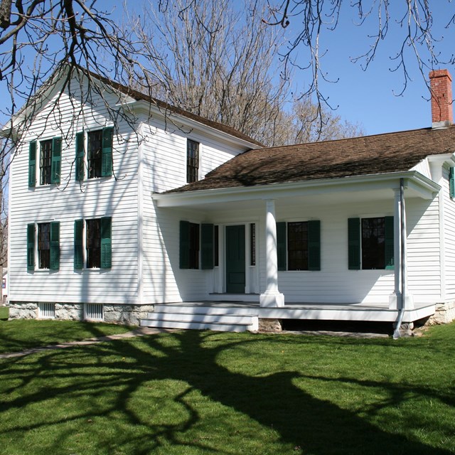 Two-story white house with green shutters and a covered front porch