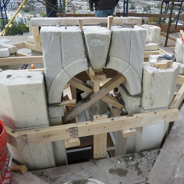 A granite arch for a window being put back together with wooden frame materials.