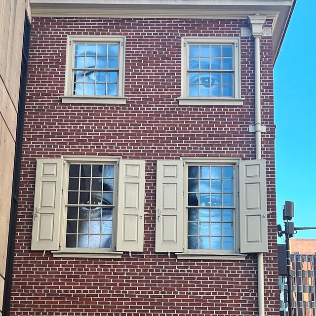 Three story brick rowhouse shows images of eyes peering out of the windows.