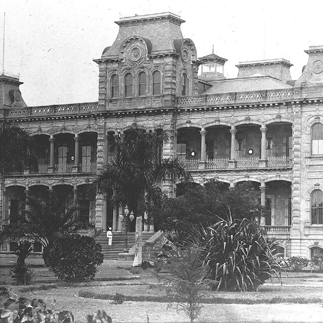 Ornate stone building with palm trees in front