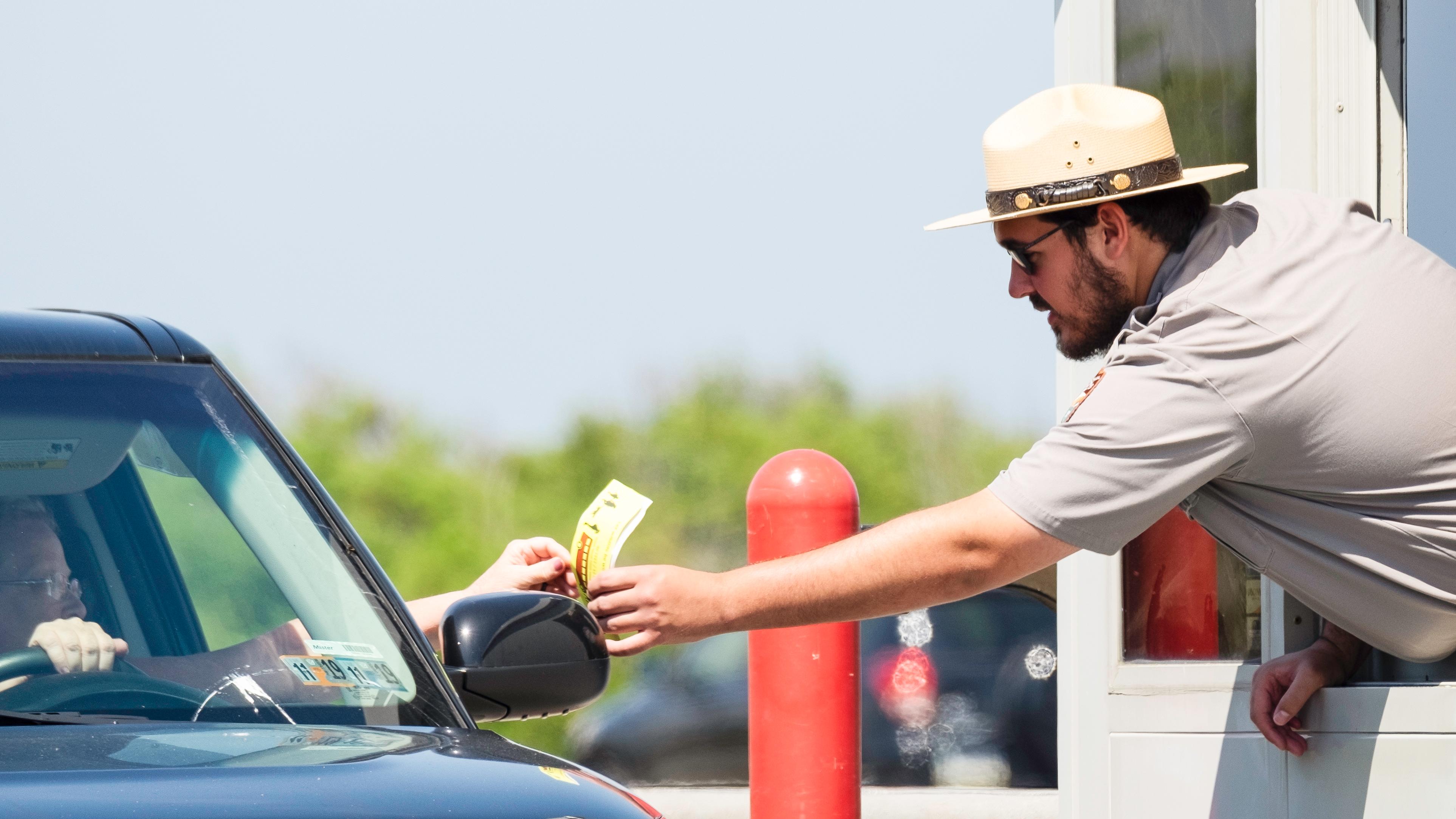 Fee ranger handing pass to visitor in vehicle.