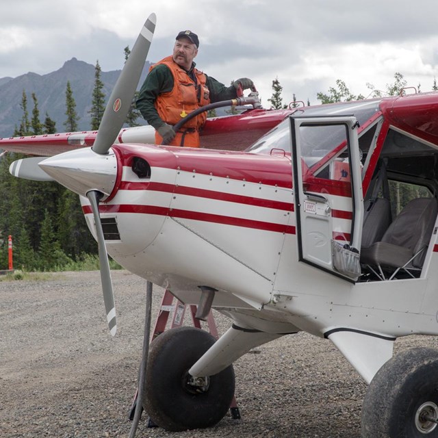 Pilot with his plane on a gravel runway