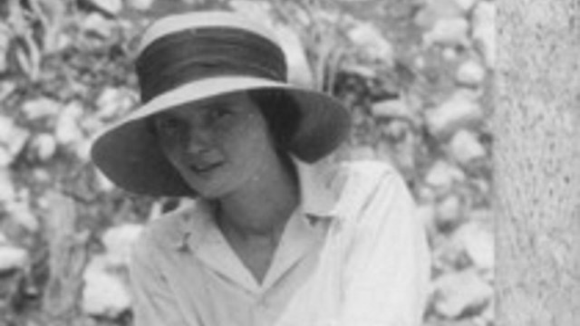 A woman holding a shovel smiling at the camera.