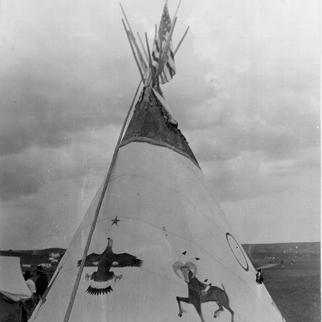 a historic photo of a tipi with paintings of animals on the outside of it
