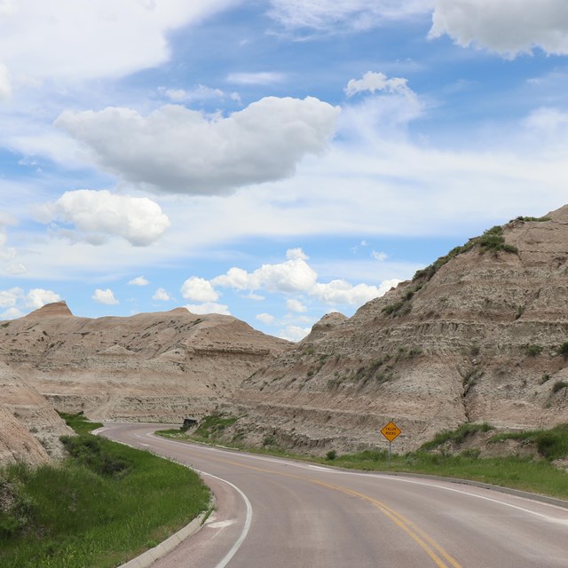 a paved road extends and turns to the left into badlands buttes.