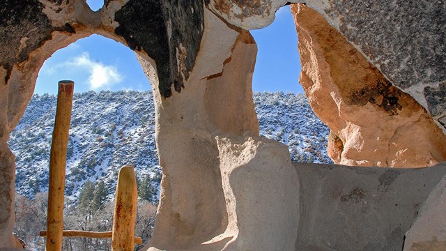 The view from inside a cavate looking out onto a snowy cliffside.