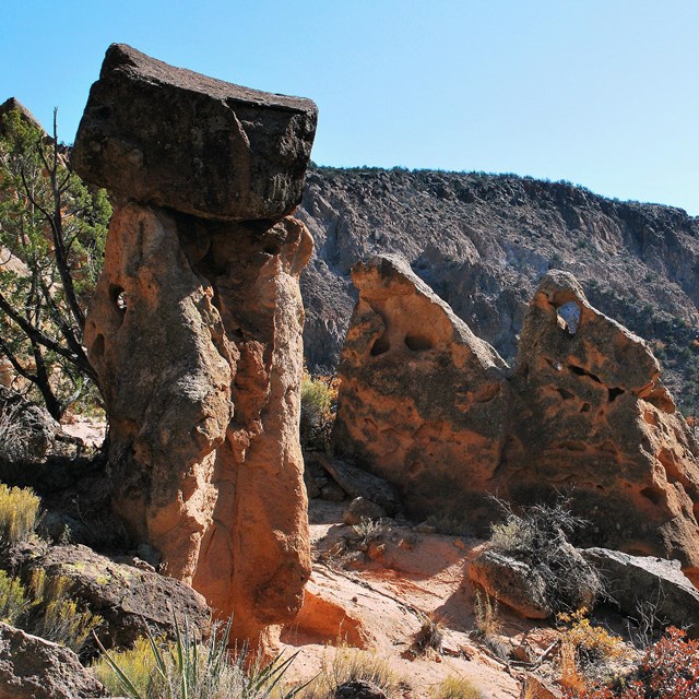 Red and pink rocks stand tall against a blue sky.