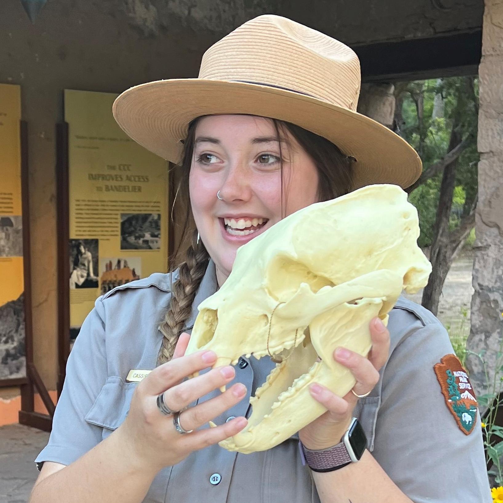 A female park ranger holding a replica bear skull. 