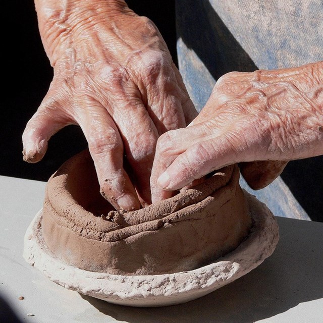 A pair of hands making a clay pot.