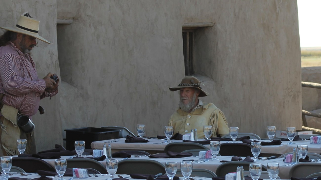 A living historian sits at a table set for a catered dinner