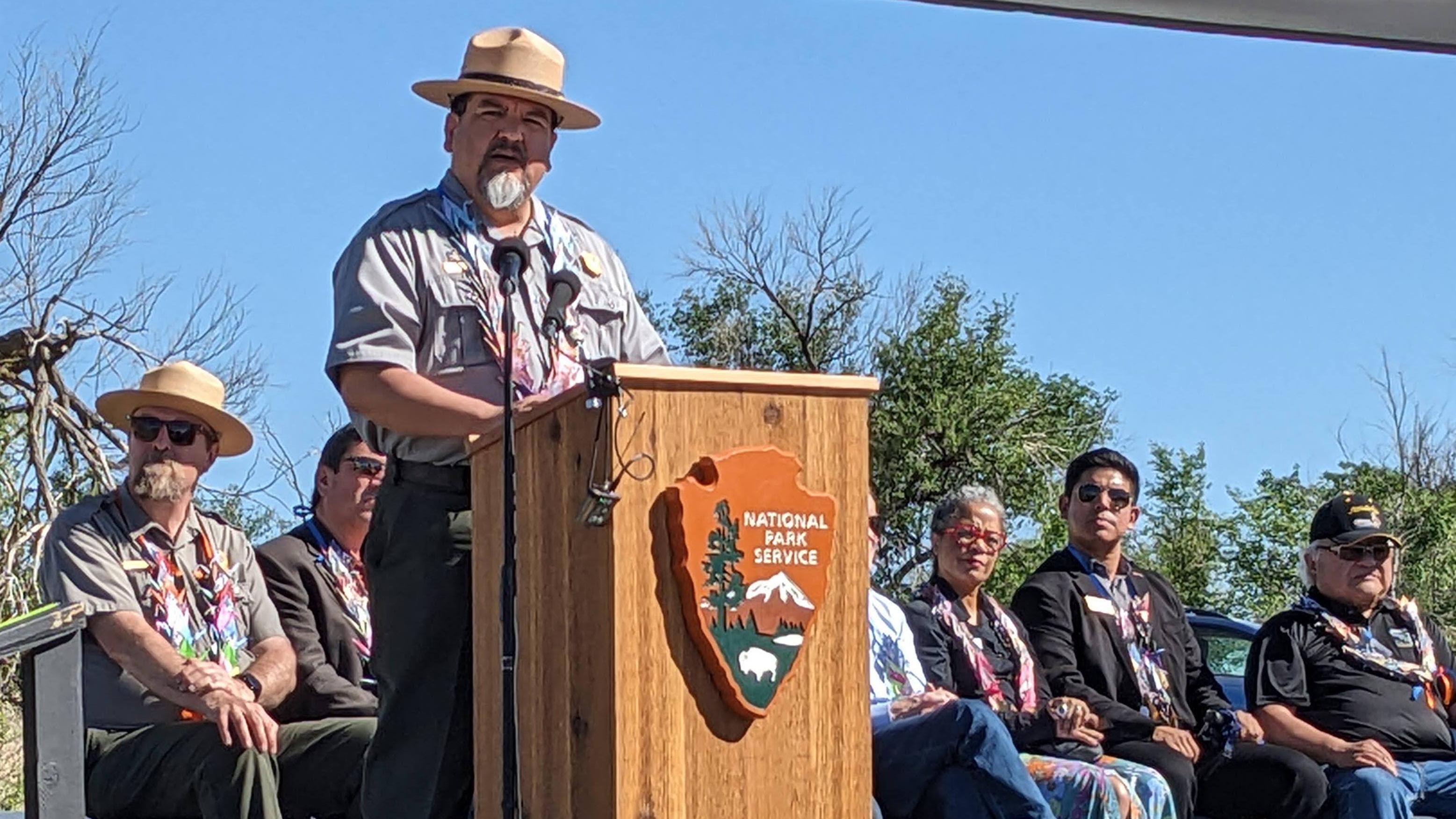 NPS Director, Chuck Sams, speaks into a microphone at Amache's ribbon cutting ceremony. 