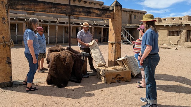 A park ranger explains the use of the wooden fur press inside the fort to a group of visitors. 