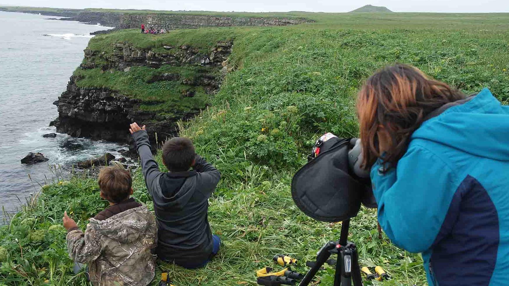Kids participate in spotting birds along the rocky coast.