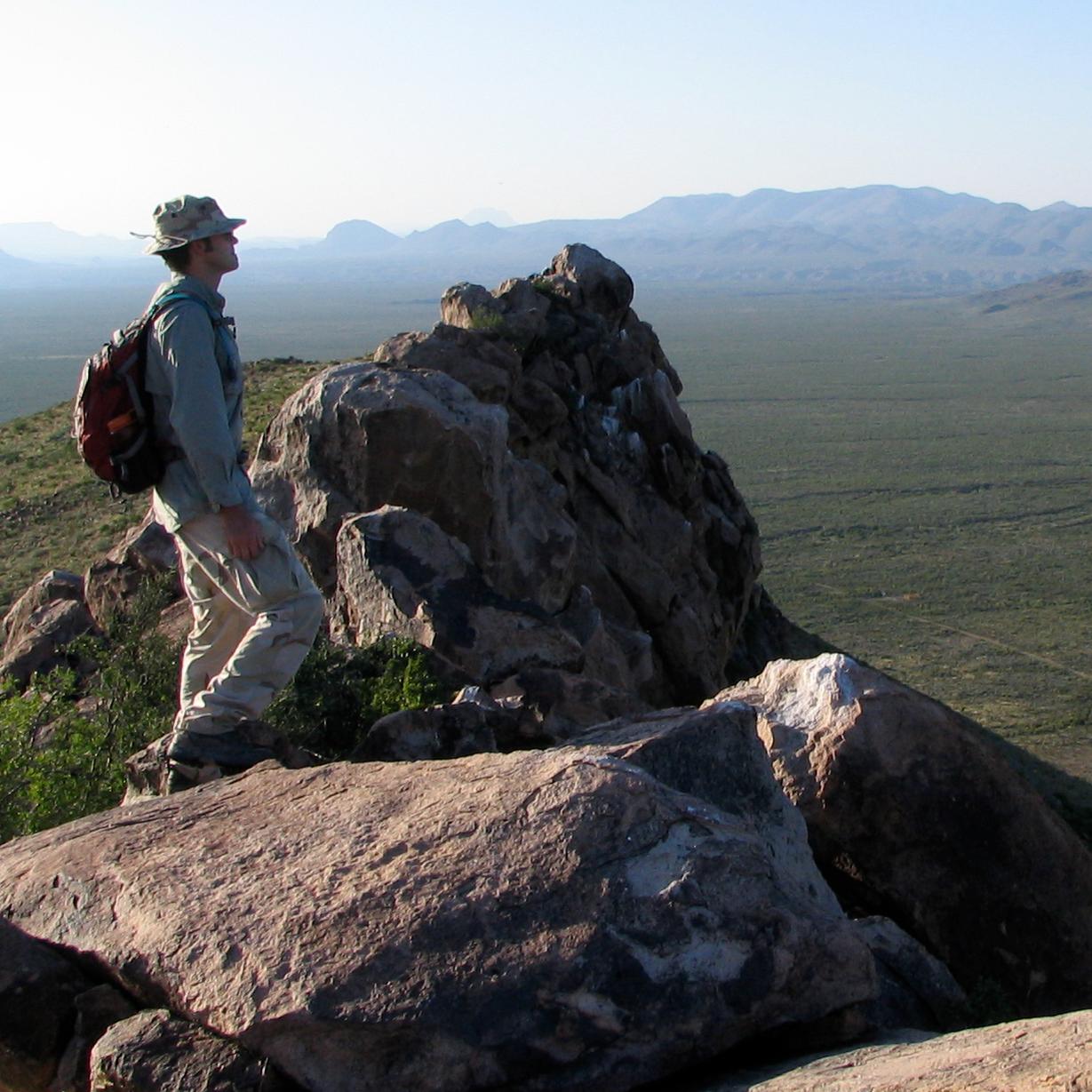 A hiker gazes into the vast desert and mountains of Big Bend.