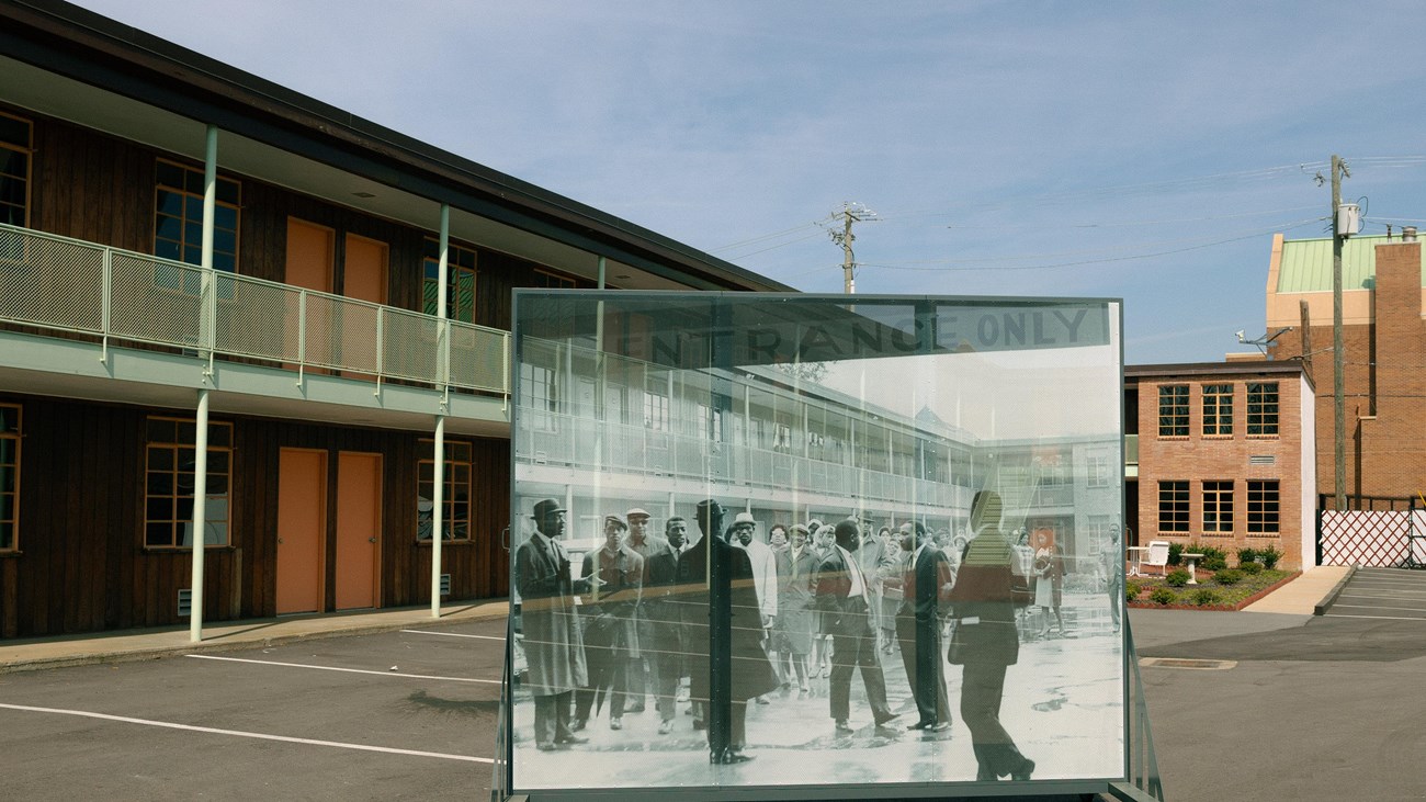 An oversized historic photo is propped on a frame in front of a two-story brick structure.