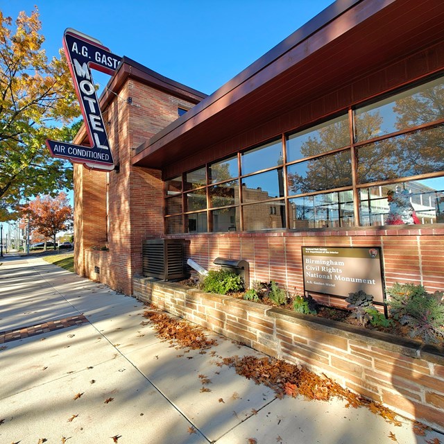 A sign reading A.G. Gaston Motel hangs from the side of an upscale 1950's motel.