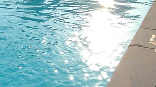 sunlight glistens across waves in deep end of pool