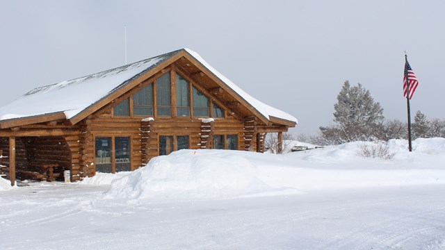 A log cabin style building and adjoining parking lot both covered with fresh snow.
