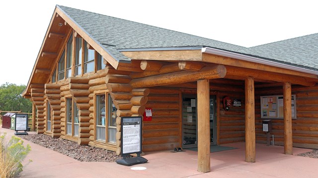 A log cabin style building with informational signs in front.